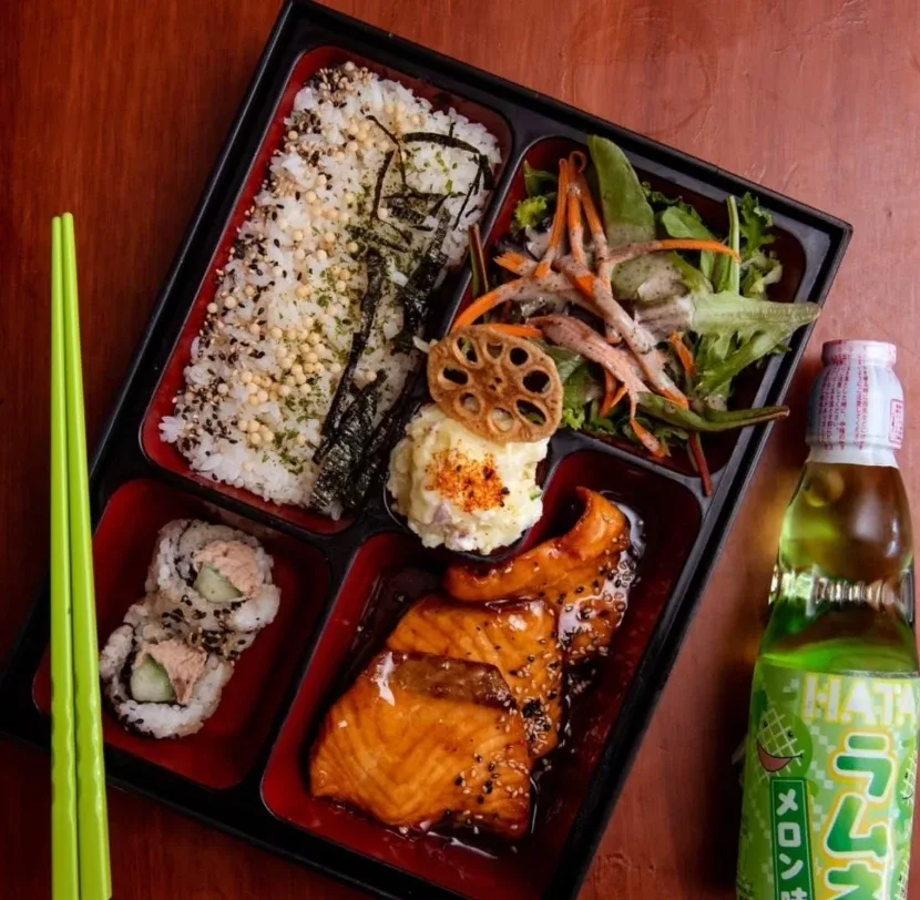 A Kaze Bento bento box with teriyaki salmon, seasoned rice, salad, potato salad and a sushi roll