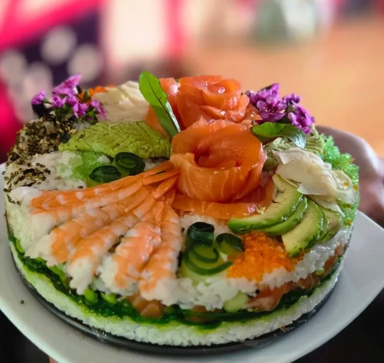 A Kaze Bento sushi cake topped with salmon roses, prawns, avocado, tobiko and flowers