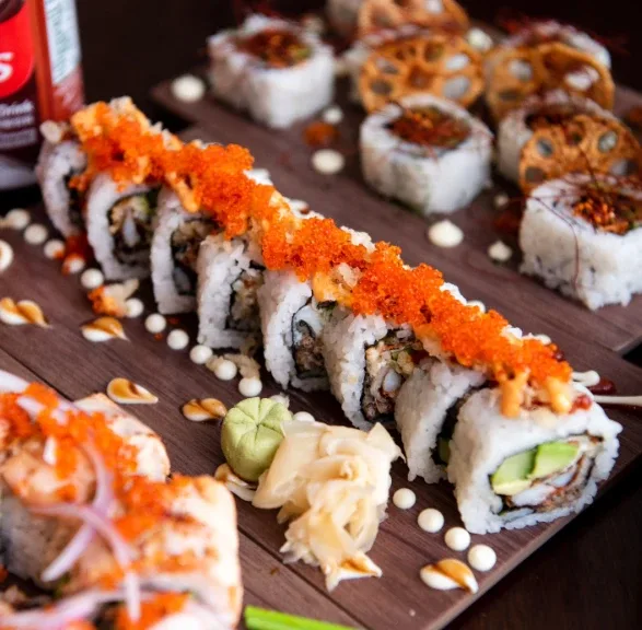 Kaze Bento sushi rolls topped with tobiko and sauce, with lotus chips, pickled ginger and wasabi